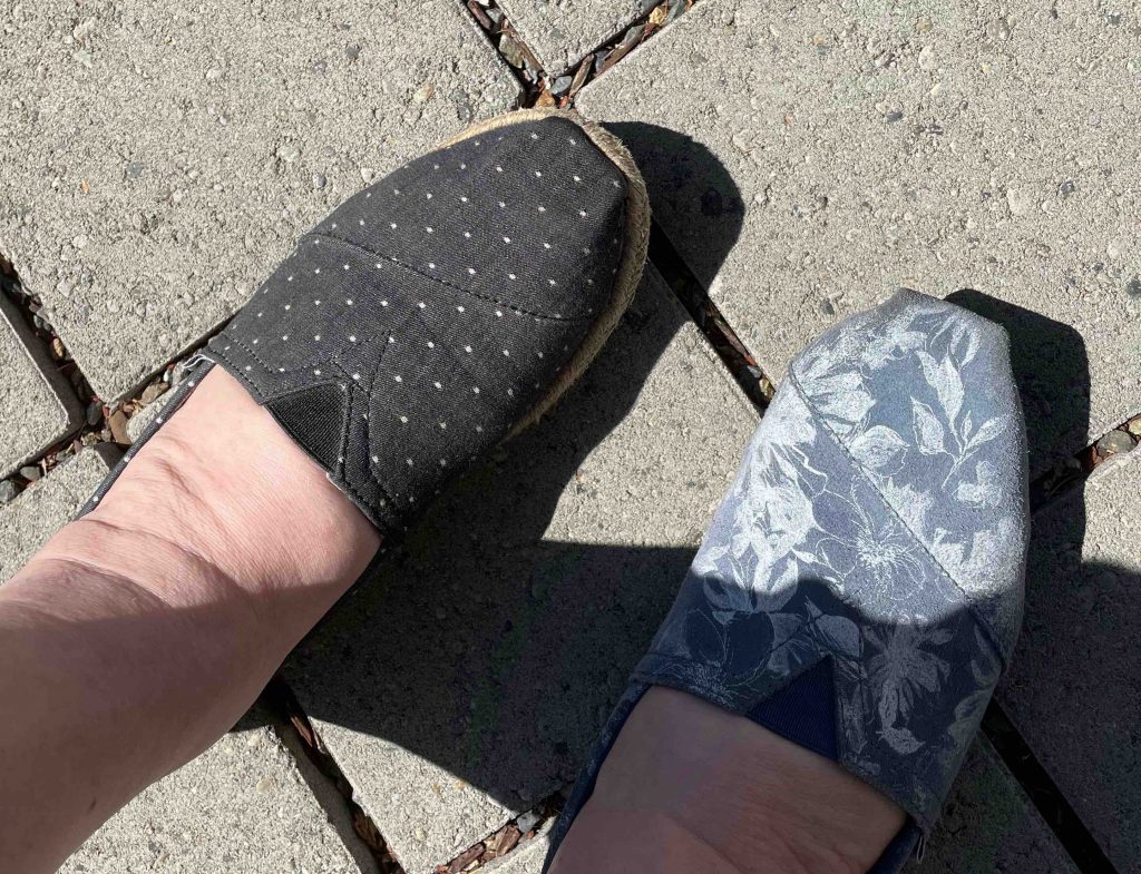 One shoe is black with white polka dots, the other shoe is blue with white flowers.